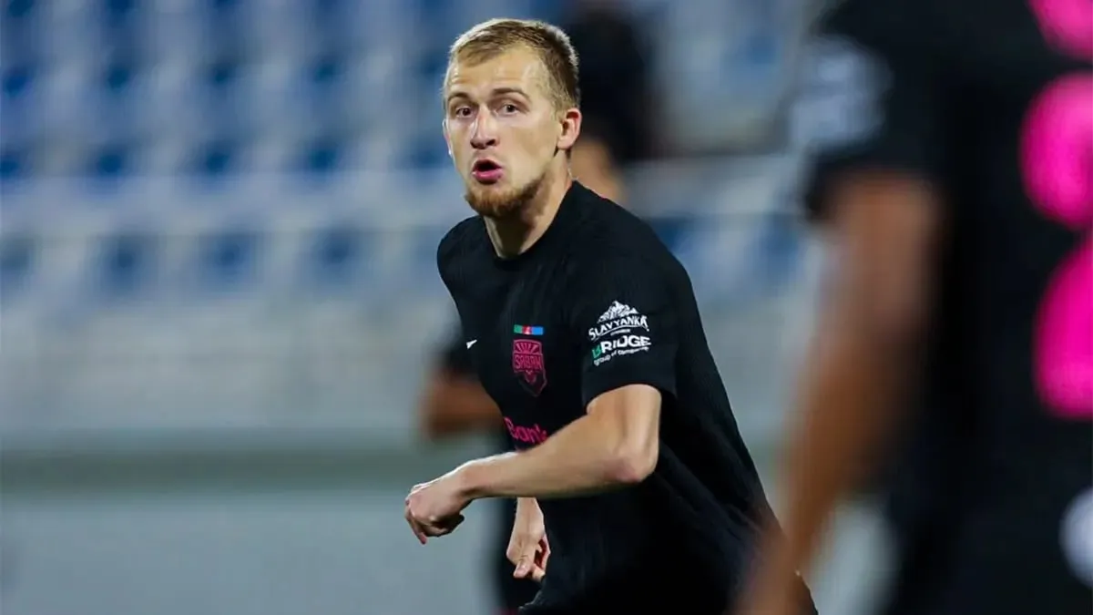 Aleksey İsayev mətbuat konfransında, arxa planda futbol stadionu