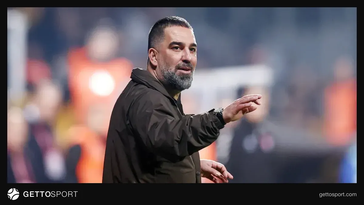 Arda Turan kostyumda tribunaya baxır, Türkiyə bayrağı fonunda