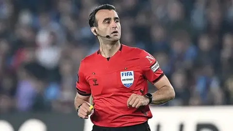 Hakem Atilla Karaoğlan düdük tutarken stadyum arka planı