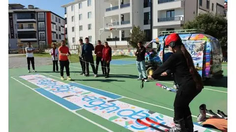Okul bahçesinde çadır pistte kayak eğitimi veren Canser Atila ve öğrenciler