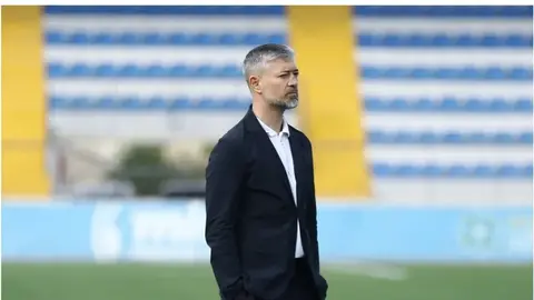 Elvin Məmmədov mətbuat üçün danışır, arxada futbol zalı fonu
