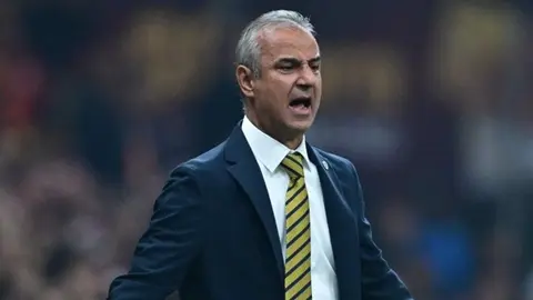 Elvir Baliç konuşurken yakın plan, arka planda stadyum görünümü