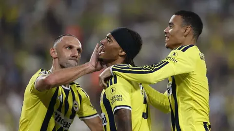 Fenerbahçe forması giymiş futbolcular ve Aston Villa logosu