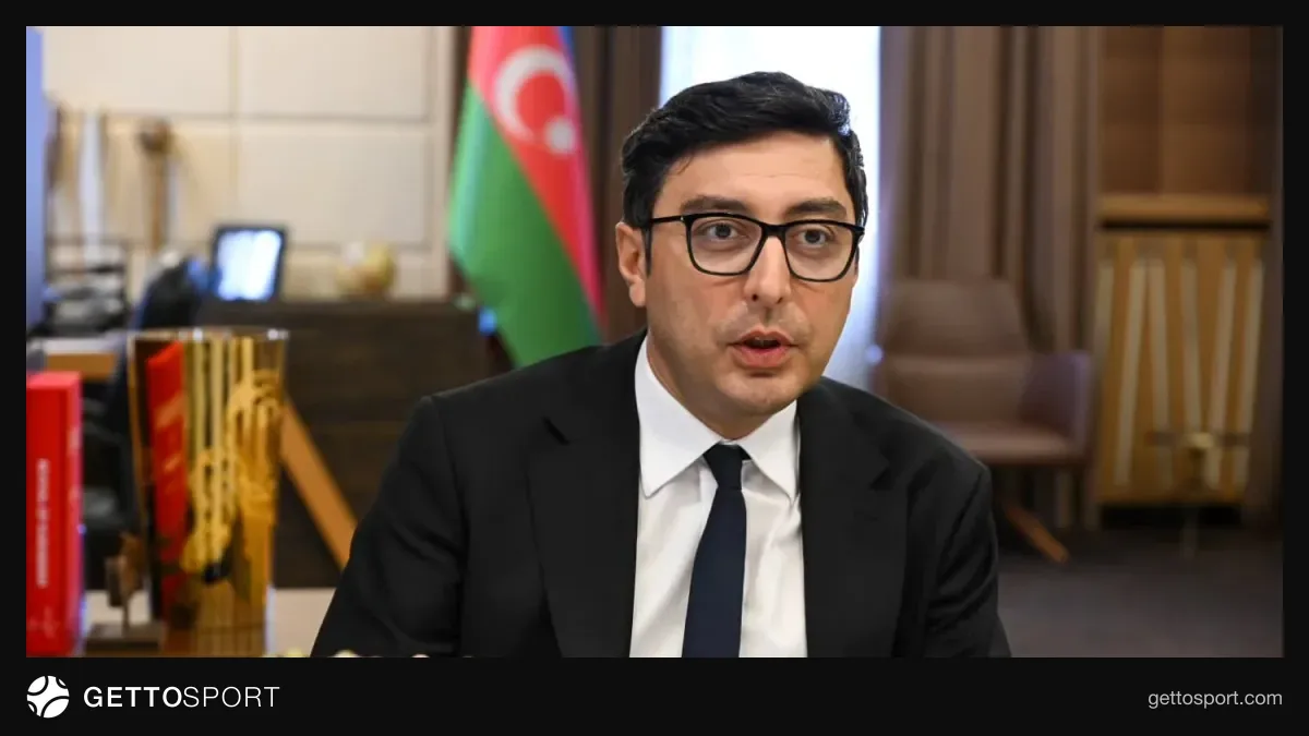 Fərid Qayıbov mikrofona danışır, arxa planda ultramarafon iştirakçıları