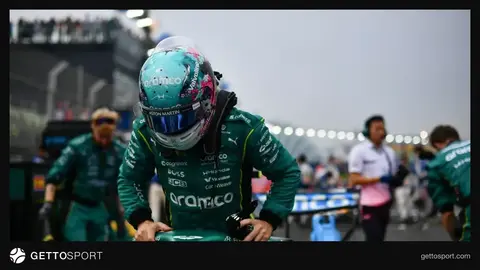 Fernando Alonso mikrofon qarşısında müsahibə verir, arxa planda Aston Martin loqosu