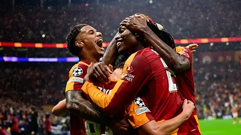 Galatasaray formasıyla sahada yürüyen futbolcular, tribünlerde taraftarlar