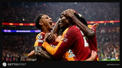 Galatasaray formasıyla sahada yürüyen futbolcular, tribünlerde taraftarlar