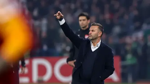 Okan Buruk basın toplantısında konuşurken, arka planda Galatasaray oyuncuları ve Konya Büyükşehir Stadı