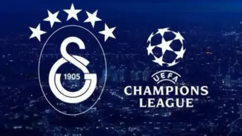 Galatasaray formasıyla sahada futbolcular ve tribünde taraftarlar