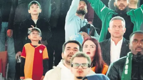 Sarı-kırmızılı forma giymiş bir çocuk Konyaspor tribünlerinde otururken