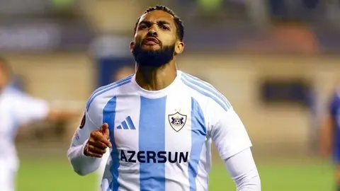 Juninyo Olavio futbol formasında, mikrofona danışarkən
