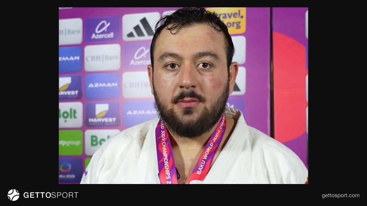Kənan Qasımov medalla dayanıb və salam verir