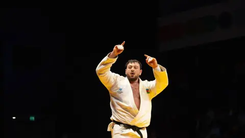 Kənan Qasımov medalı ilə tribunaya salam verir