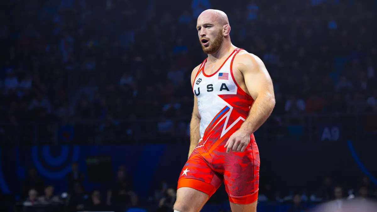 Kyle Snyder kupayla sevinç gösterisi, arka planda minderde mücadele görüntüsü