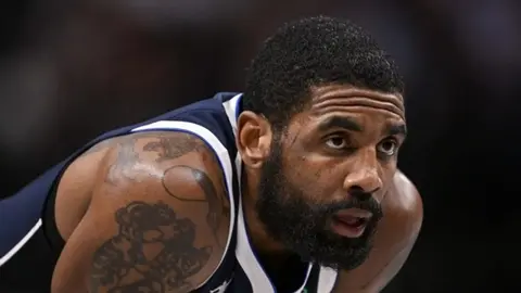 Kyrie Irving maç formasıyla top sürerken düşünceli görünüm