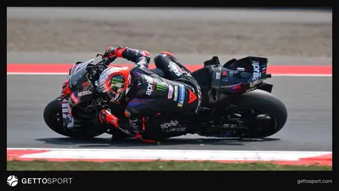 Marco Bezzecchi podyumda kaskıyla yarış motosikleti arka planında