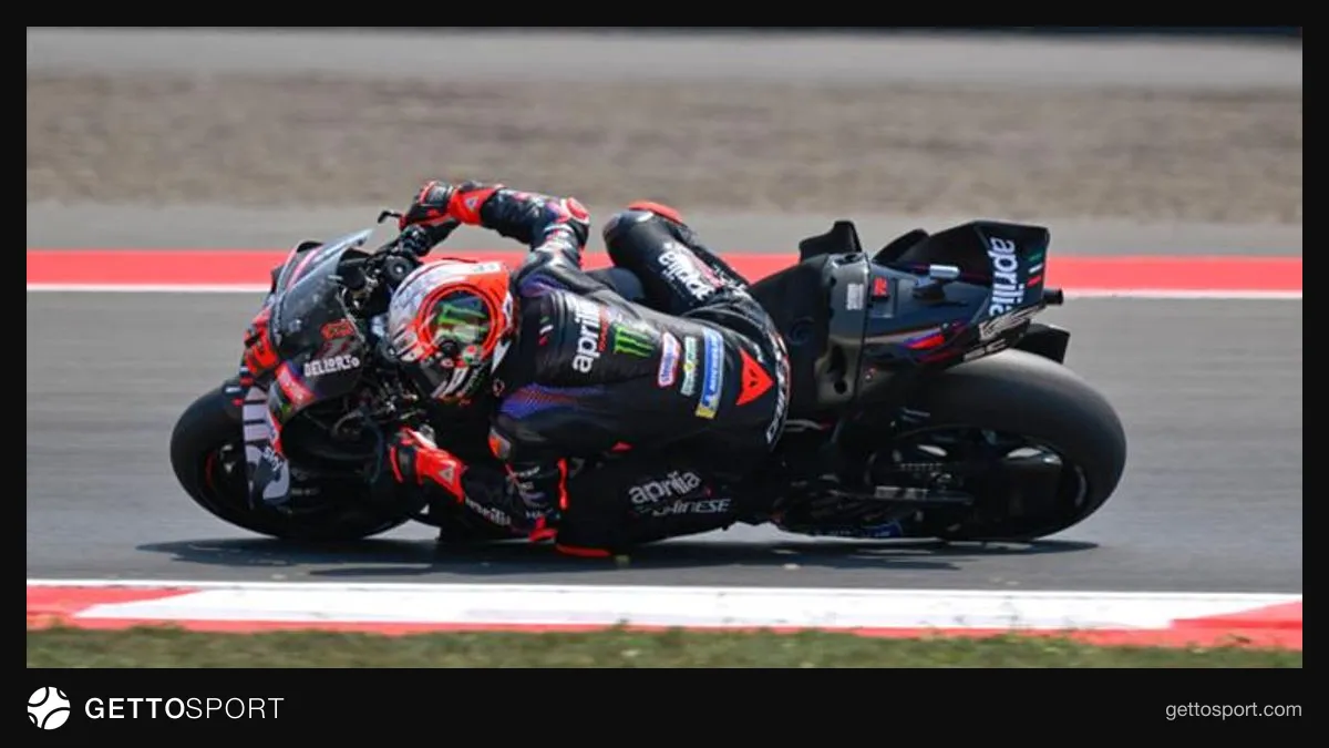Marco Bezzecchi podyumda kaskıyla yarış motosikleti arka planında