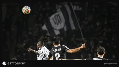 Stadionda topla oynayan futbolçular və tribunada azarkeşlər