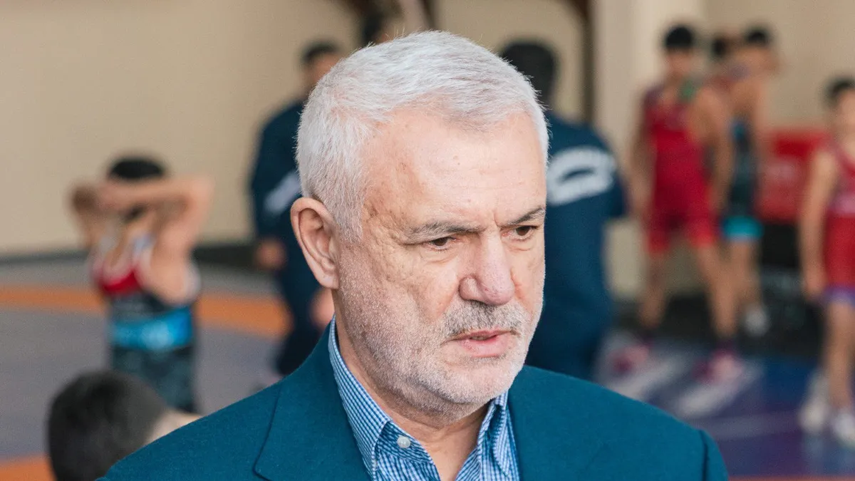 Namiq Əliyev portreti və güləş tədbiri fonunda