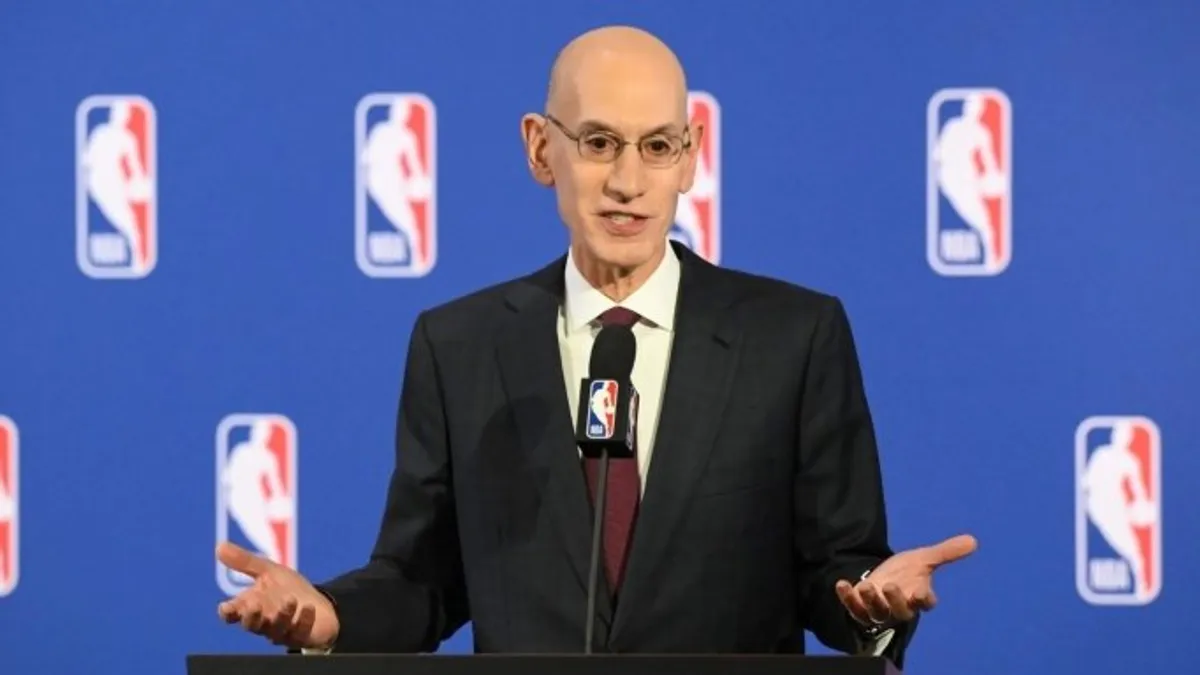 NBA logosu ve salon içerisinde basketbol maçı oynanan bir an