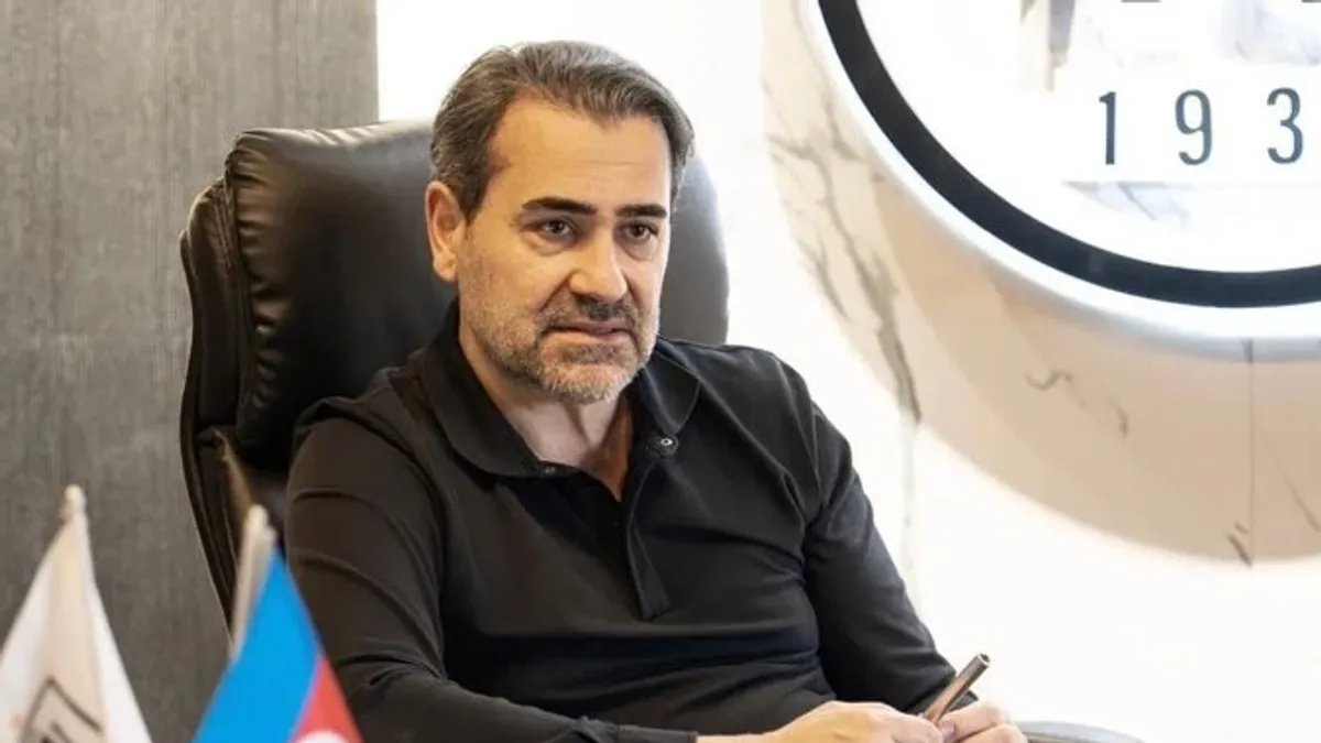 Neftçi klubunun rəhbəri Cenk Sümer klubun bayrağı qarşısında danışır