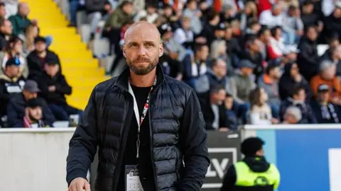 Nils-Ole Buk mətbuat konfransında, arxa fonda futbol meydanı