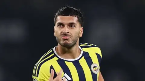 Rams Park'ta maç izleyen gözlemciler ve Oğuz Aydın top sürerken