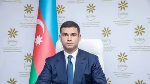 Orxan Məmmədov mikrofon qarşısında çıxış edir, püşkatma tədbiri