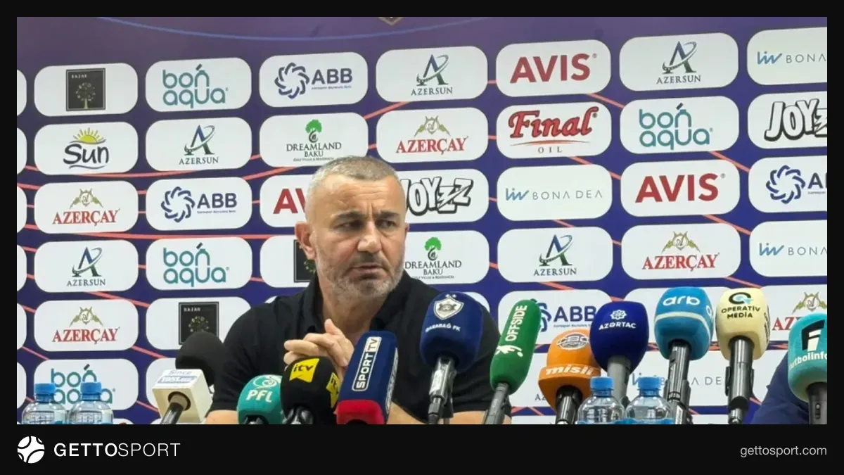 Qurban Qurbanov mətbuat konfransında, arxa planda futbol stadionu