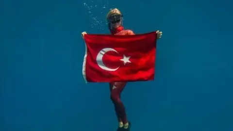 Şahika Ercümen su altında Türk bayrağıyla
