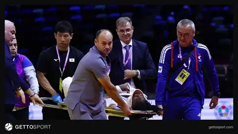 Səhnə: cüdo yarışmasında tatami üzərində xərəkdə aparılan idmançı