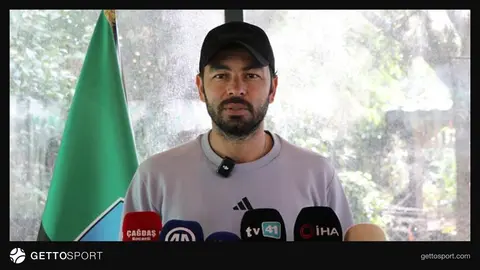 Selçuk İnan antrenman öncesi konuşurken, Kocaelispor oyuncuları sahada çalışıyor