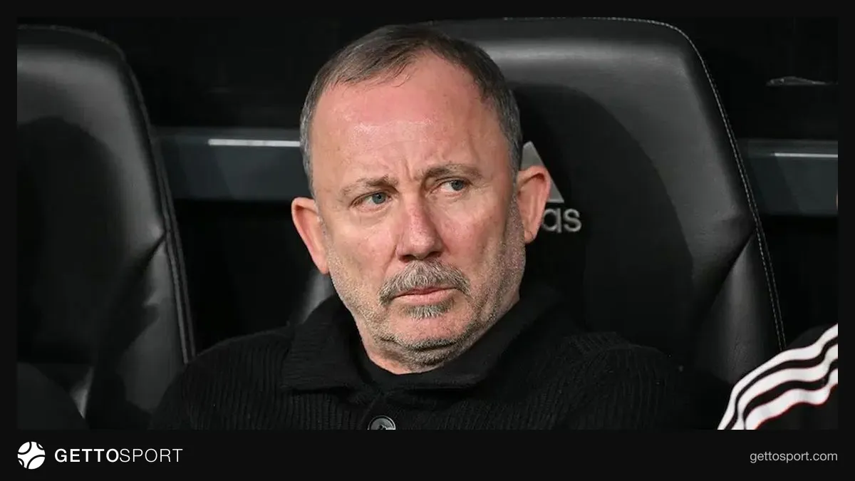 Sergen Yalçın konuşurken mikrofon önünde, arka planda Galatasaray forması