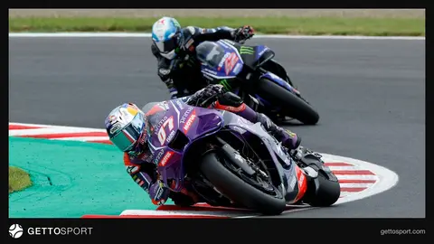 Toprak Razgatlıoğlu pistte motosikletiyle helm ve yarış kıyafetiyle konuşurken