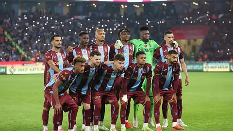 Trabzonspor formasıyla saha kenarında yürüyen futbolcular ve teknik ekip