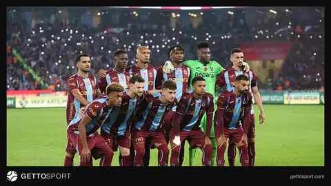 Trabzonspor formasıyla saha kenarında yürüyen futbolcular ve teknik ekip
