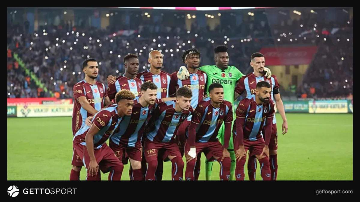Trabzonspor formasıyla saha kenarında yürüyen futbolcular ve teknik ekip