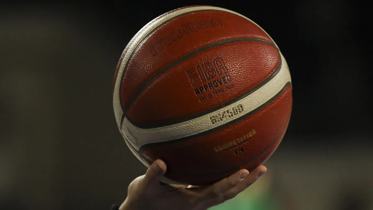 Saha kenarında başlayan basketbol karşılaşması için hazırlık yapan oyuncular ve hakemler