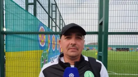 Aziz Kambarov mətbuat konfransında, fonunda U-15 dünya çempionatının loqosu
