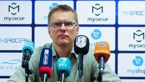 Valdas Dambrauskas mətbuat konfransında, stadion fonunda