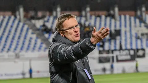 Valdas Dambrauskas mətbuat konfransında, arxada futbol stadionu