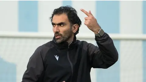 Vaqif Cavadov mətbuat önündə danışır, arxa planda U-15 mundial afişası
