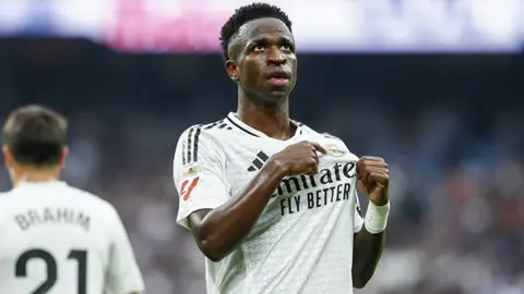 Vinisius Junior ağ rəngli Real Madrid formanında topa doğru qaçır