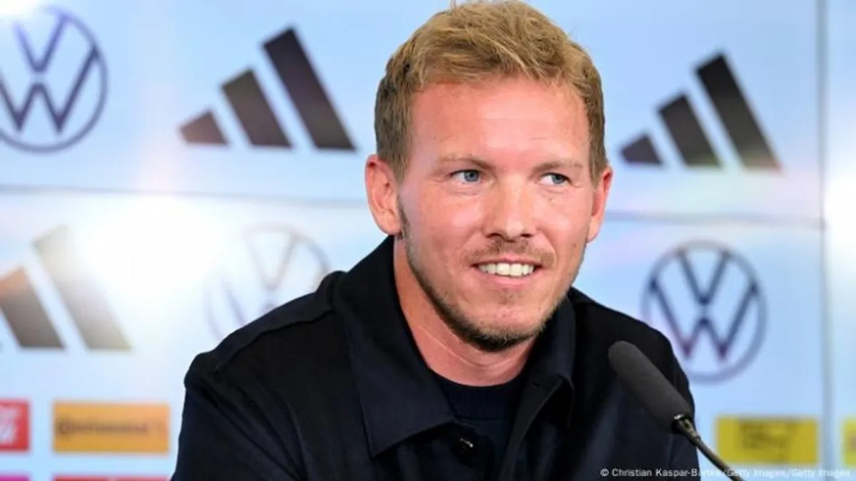 Yulian Naqelsmann ağ kostyumda stadion kənarında
